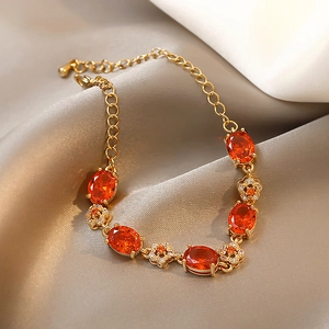 Gros plan d'un bracelet doré avec des pierres orange ovales et détails de fleurs en zircon