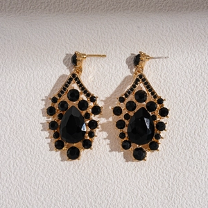 Macro detail of retro gold earrings featuring black teardrop stones and intricate carvings
