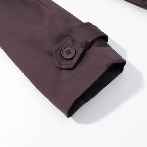 Gros plan du poignet réglable avec bouton à quatre trous sur trench-coat marron foncé