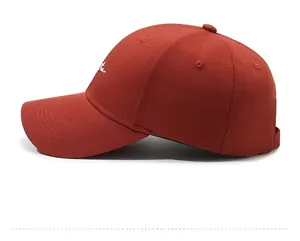 Detail of embroidered letters on a brick red cotton baseball cap with twill texture