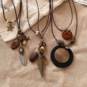 Detail of bohemian necklaces with vintage feathers, wood beads and turquoise on burlap