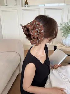 Detail view of a large brown chiffon polka dot scrunchie styled in a low ponytail