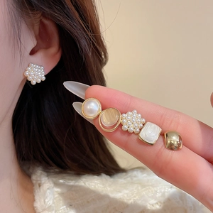 Detail showing various gold-plated zircon pearl stud earrings worn on the earlobe