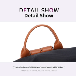 Detail view of the brown synthetic leather handle with precision stitching on a black nylon bag