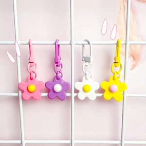 Colorful resin flower keychains with plastic spring hooks on a white grid display
