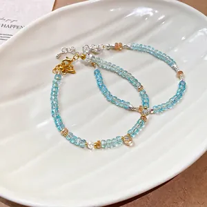 Handmade light blue beaded crystal bracelets with gold and silver lobster clasps in a dish