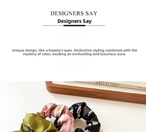 Detailed view of silk satin daisy floral scrunchies in olive, pink, and black colors