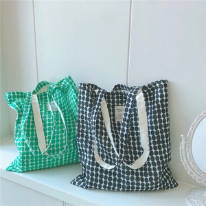 Detailed view of green and black cotton tote bags with polka dot patterns and woven handles