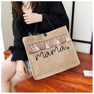 Detail of jute tote bag with Mama print and colorful fringes held by a model