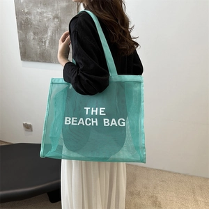 Minimalist large mesh tote bag in mint green featuring The Beach Bag white lettering