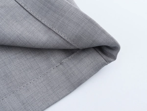 Vue macro détaillée montrant la texture du tissu gris et les coutures de ce pantalon