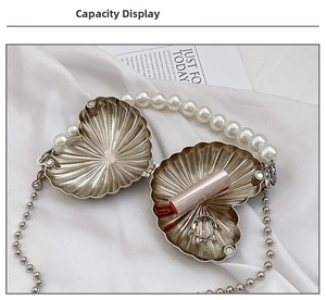 Macro detail of silver heart-shaped evening clutch bag with pearl handle and capacity for lipstick