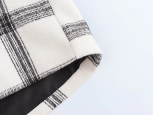 Close-up of black and white plaid wool blend fabric with smooth black inner lining texture