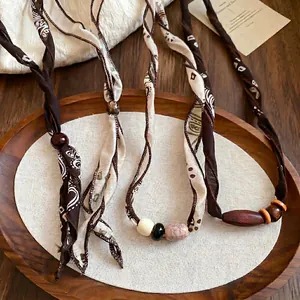 Maillard style brown paisley silk scarf necklace with ethnic beads on wooden tray