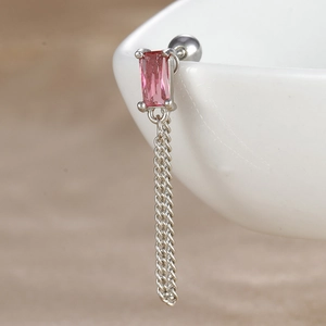Détail d'un piercing hélix avec zircon rose et double chaîne argentée sur céramique