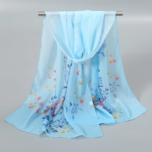 Détail d'une écharpe en mousseline bleu ciel avec de délicats motifs floraux suspendus