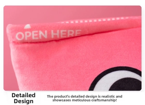 Detail of pink axolotl plush pillow featuring 'OPEN HERE' text and soft texture