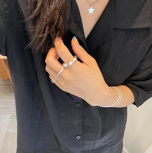 Detail of silver irregular open ring with beaded bracelet and star pendant on model