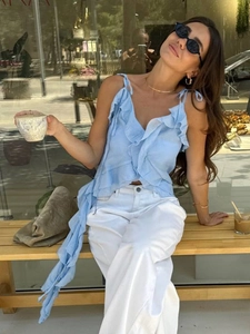 Detail of light blue ruffled camisole top with flowy side streamers for summer vacation style