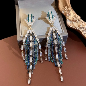 Detail of luxury emerald fringe earrings with gold tassels and crystals in a box