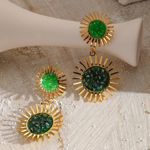 Gold sunflower drop earrings with green stone inlay on elegant textured background