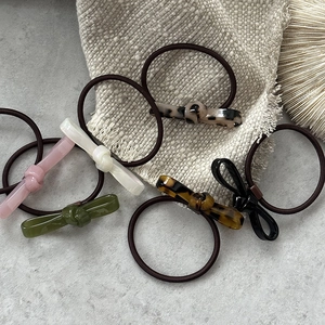Flat lay of small bow-knot hair ties in multi-color resin on grey concrete surface