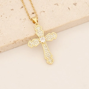 Macro view of 18K gold plated cross pendant with cubic zirconia on stone surface