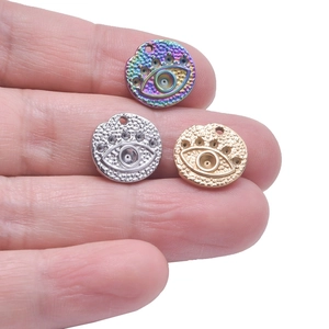 Three evil eye pendants in gold, silver, and rainbow colors on fingertips