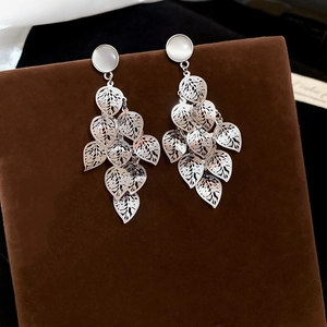 Close-up of elegant leaf tassel earrings with cat eye stone on dark velvet