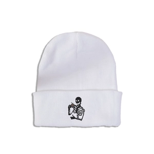 Détail du bonnet blanc en maille côtelée avec broderie de squelette buvant du thé