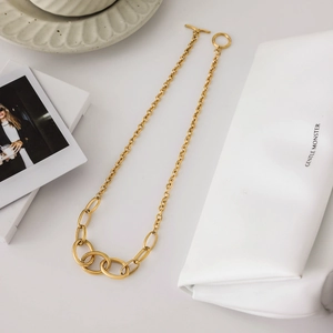 Gold stainless steel link chain necklace with OT toggle clasp on a minimalist desk