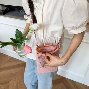 Close-up of pink embroidered mini bag with floral patterns and woven crossbody strap