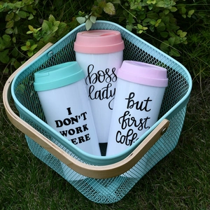 Reusable double-walled acrylic coffee mugs with Boss Lady text in a garden basket