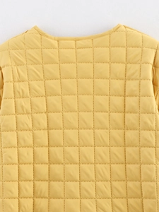 Détail d'une veste matelassée jaune montrant les coutures carrées et la texture du tissu
