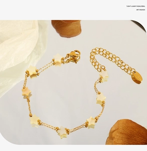 Macro shot of 18k gold plated stainless steel star charm bracelet on mirror surface