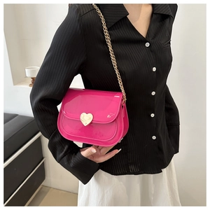 Detail of fuchsia patent leather square bag with gold heart lock and chain strap