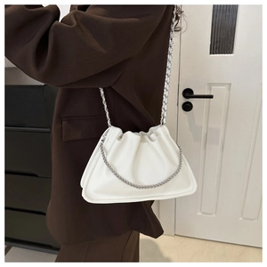 Crossbody white pleated cloud bag with silver chain strap shown on a brown blazer outfit