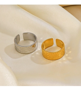 Detailed view of hammered gold and silver adjustable steel rings on beige silk fabric