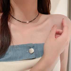 Détail d'un collier de perles de riz noires avec pendentif perle porté par un mannequin