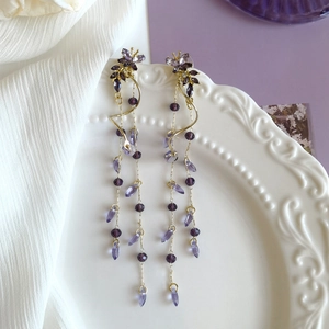 Vue détaillée des boucles d'oreilles papillon violettes avec pendentifs goutte d'eau.