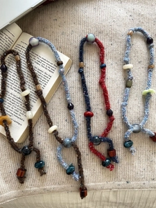 Detailed view of hand-woven cotton cord necklaces with colorful resin beads and tassels