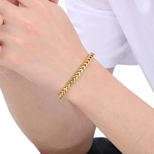 Close-up of men's gold stainless steel Franco chain bracelet on model's wrist
