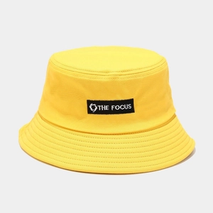 Detail view of yellow canvas bucket hat with black THE FOCUS embroidered patch