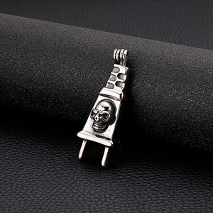 Macro detail of silver stainless steel skull power plug pendant on black leather