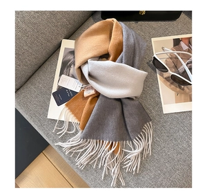 Detail view of 100% wool scarf with fringe and brand tag on stylish magazine background