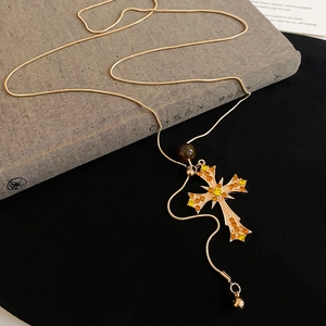 Detail view of a vintage gold cross pendant with amber rhinestones on a snake chain