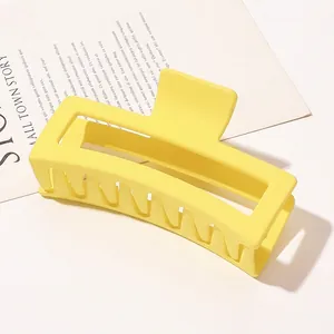 Detail view of a large rectangular matte yellow hair claw clip on a minimalist background