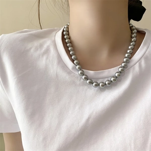 Close-up of elegant grey pearl necklace worn by a model on a white t-shirt