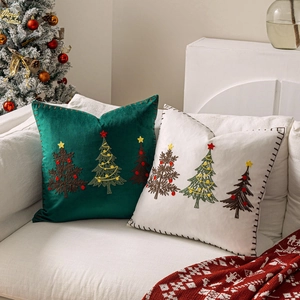 Close-up of velvet Christmas pillow covers with embroidered deer and tree patterns