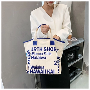 Detailaufnahme einer cremeweißen Canvas-Tragetasche mit blauem Rand und Hawaii-Aufdruck